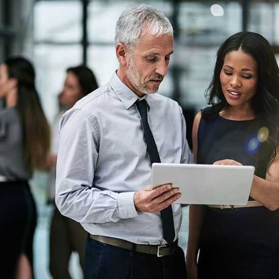 Shot of two professional coworkers using a digital tablet together at work